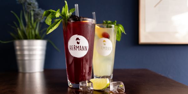Ein gelber und ein Weinroter Cocktail in Hermann-Gläsern